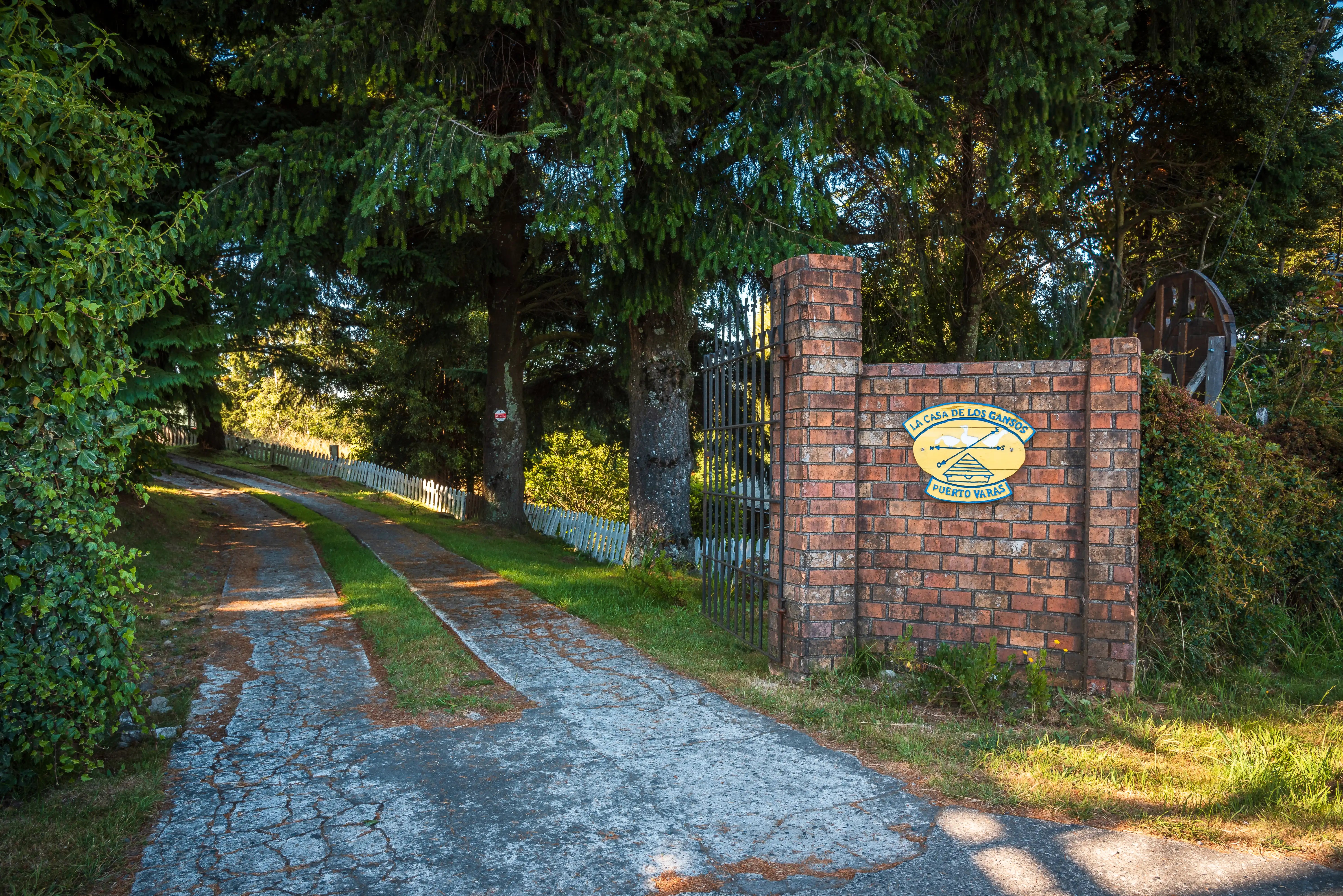Entrada principal a La Casa de los Gansos en Puerto Varas, rodeada de árboles y naturaleza.