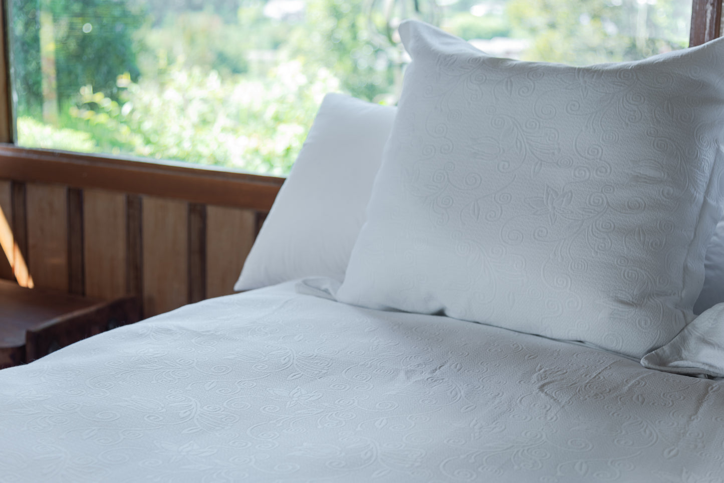 Cojín lector piqué blanco sobre cama de dormitorio, ideal para lectura y descanso – La Casa de los Gansos