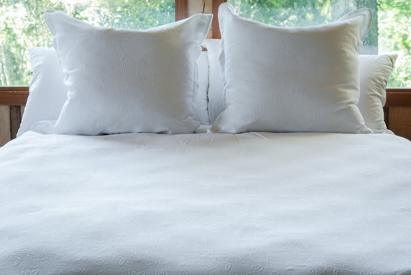 Vista general del cojín lector piqué blanco sobre cama, complemento decorativo y funcional para espacios de descanso