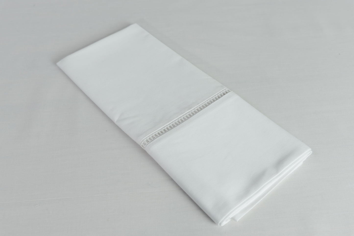 Funda de almohada deshilado de La Casa de los Gansos doblada, muestra terminación y calidad del algodón