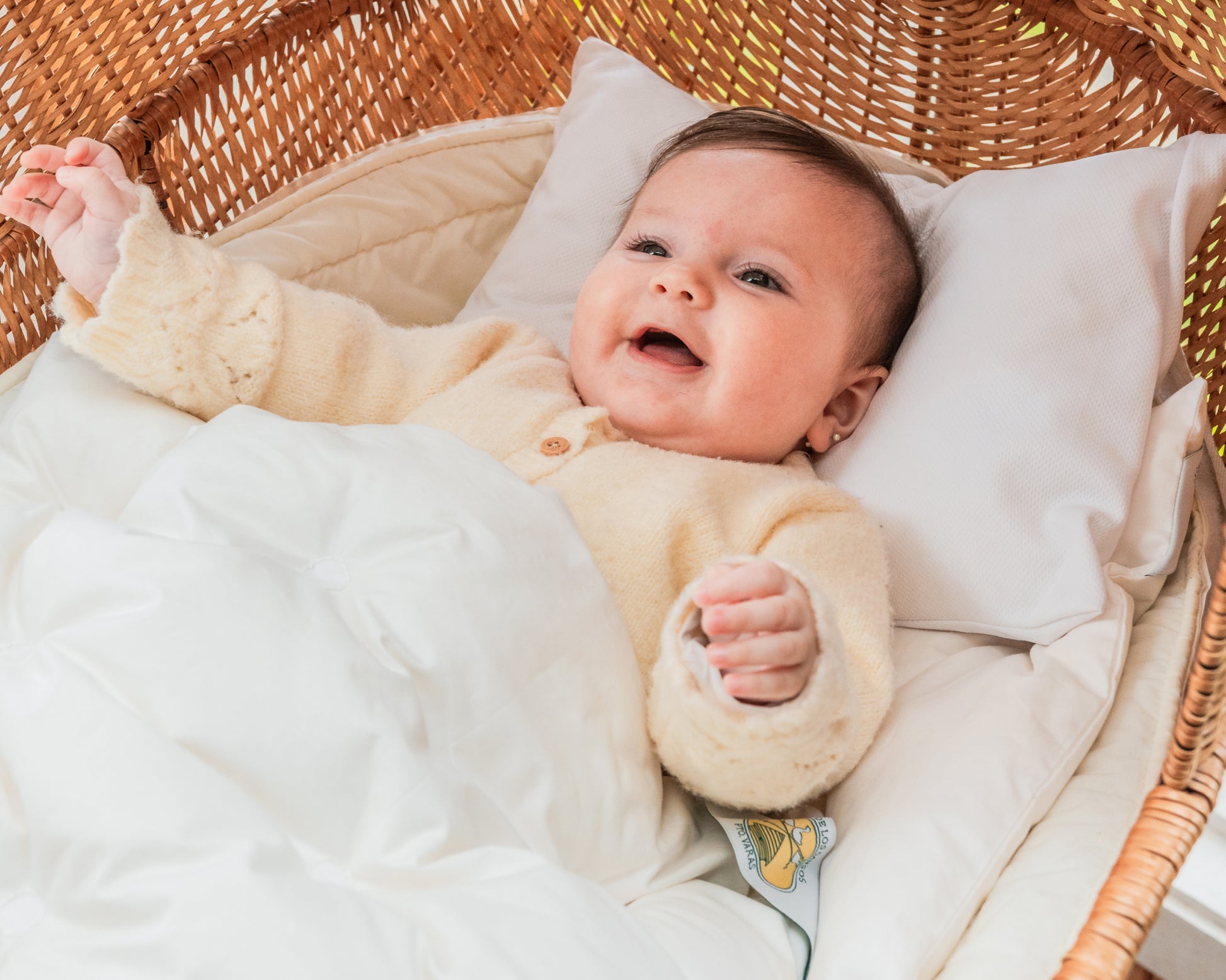 Bebé feliz apoyado sobre tutito de La Casa de los Gansos, muestra la suavidad y confort del duvet